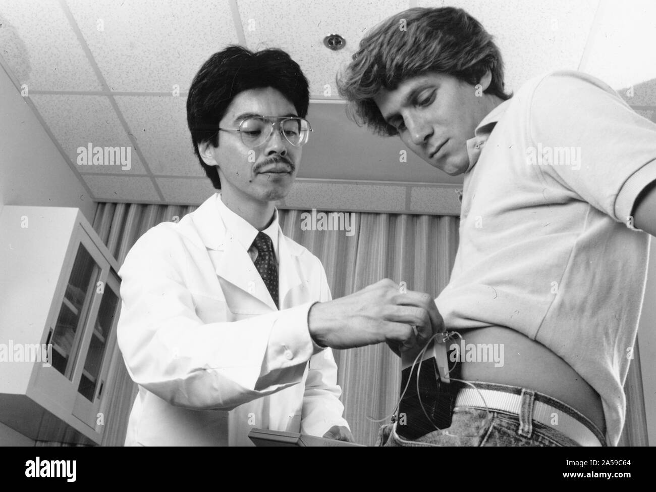 Un médecin demande à un patient dans l'utilisation d'une pompe à insuline ca. 1987 Banque D'Images