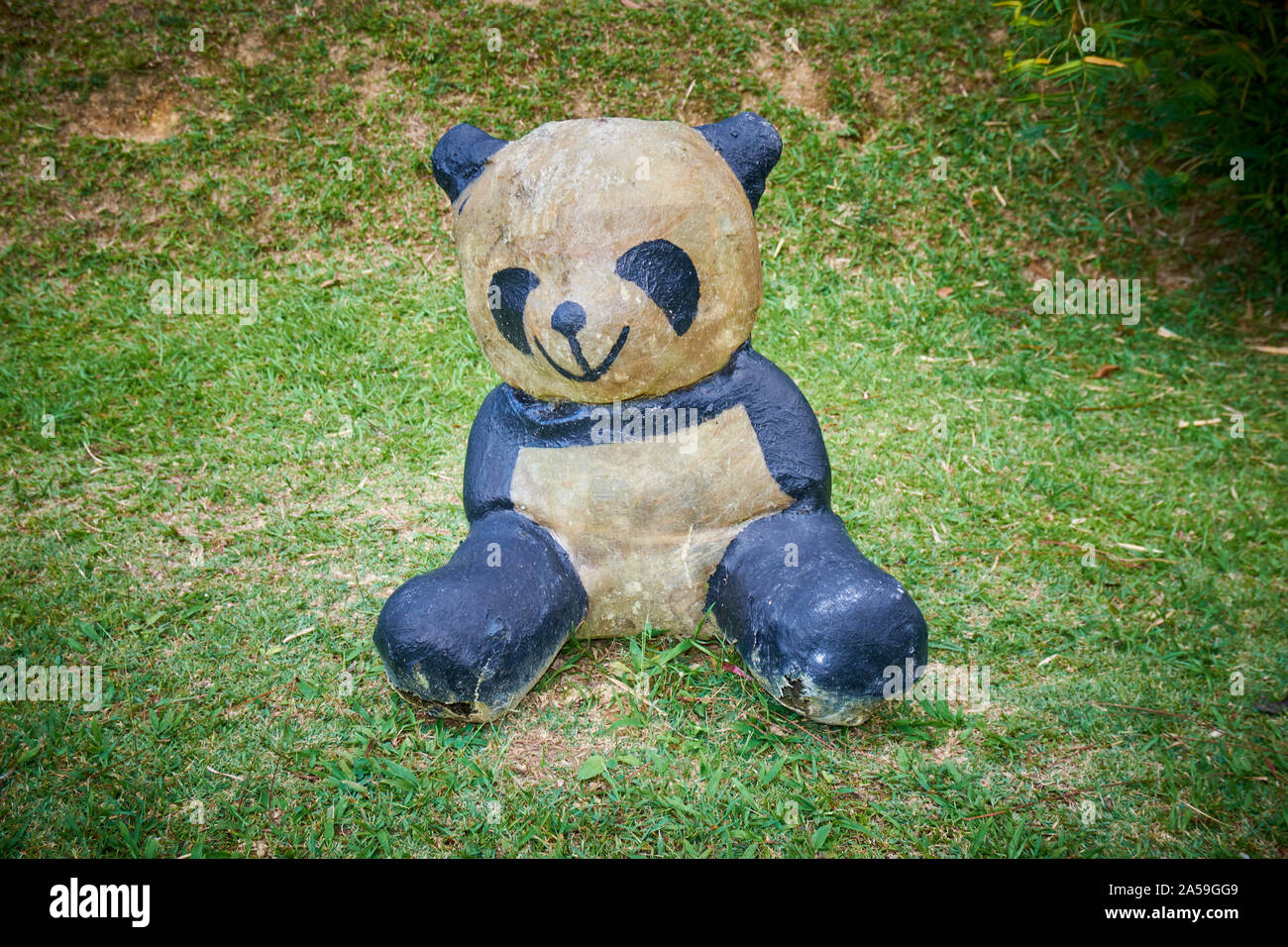 Un mignon, assise en fibre de verre, en plastique panda figure dans l'herbe, pelouse dans Fraser's Hill, la Malaisie. Banque D'Images