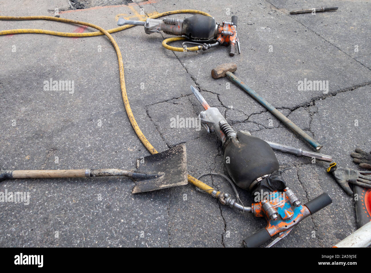 Deux marteaux perforateurs et pelle à main allongé sur un tarmac en détresse Banque D'Images