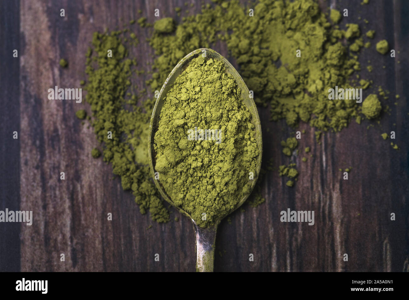 Close-up d'un vieux vert cuillère remplie de thé matcha en poudre. La cuillère est sur une vieille table en bois foncé, et une poudre est renversé sur la table. T Banque D'Images Close-up d'un vieux vert cuillère remplie de thé matcha en poudre. La cuillère est sur une vieille table en bois foncé, et une poudre est renversé sur la table. T Banque D'Images