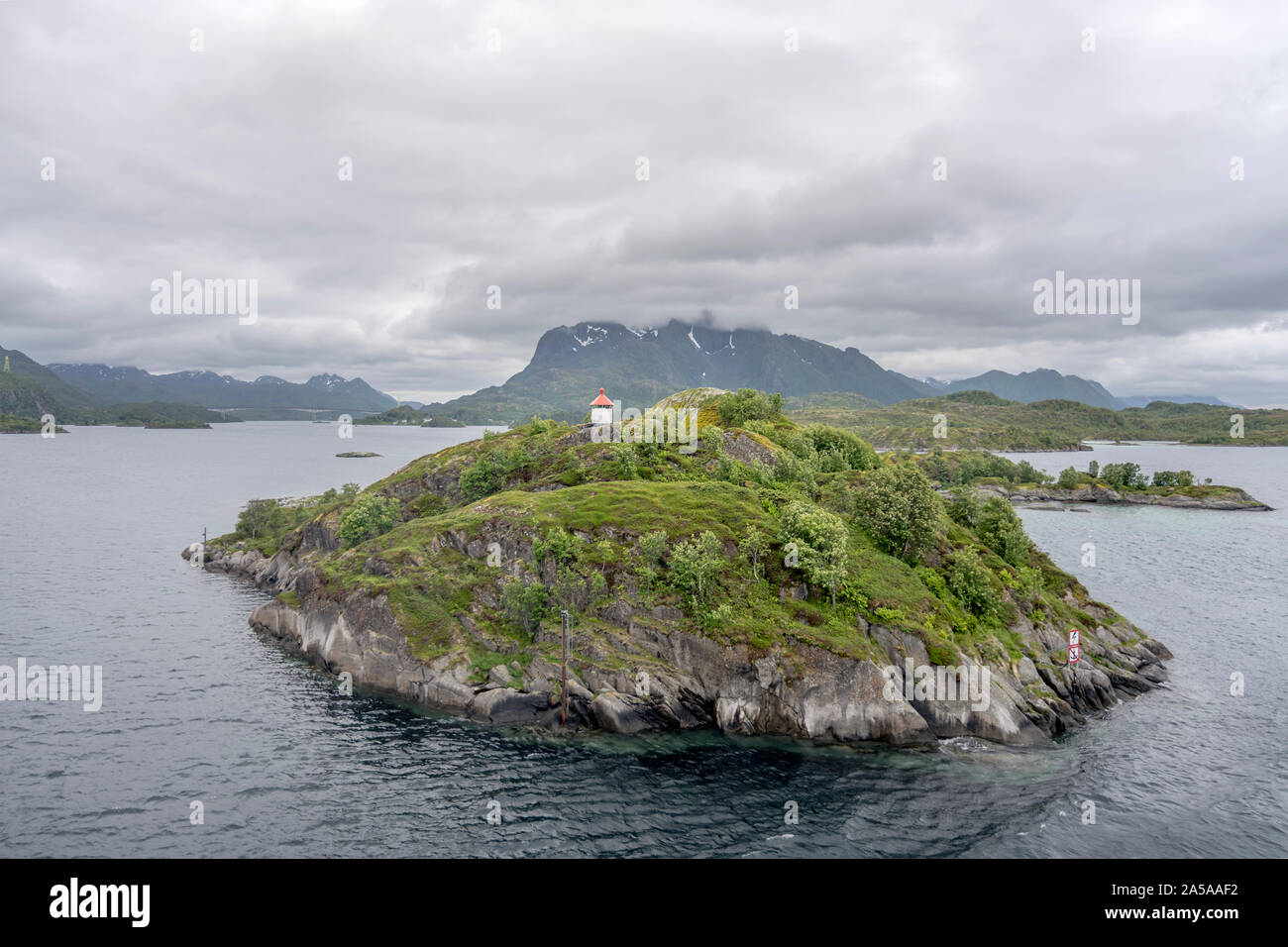 Cercle arctique paysage fjord avec petite balise sur un vert falaise de falaises vert archipel, tourné en cas de forte lumière près de nuageux, Austvagoy Brottoya Banque D'Images