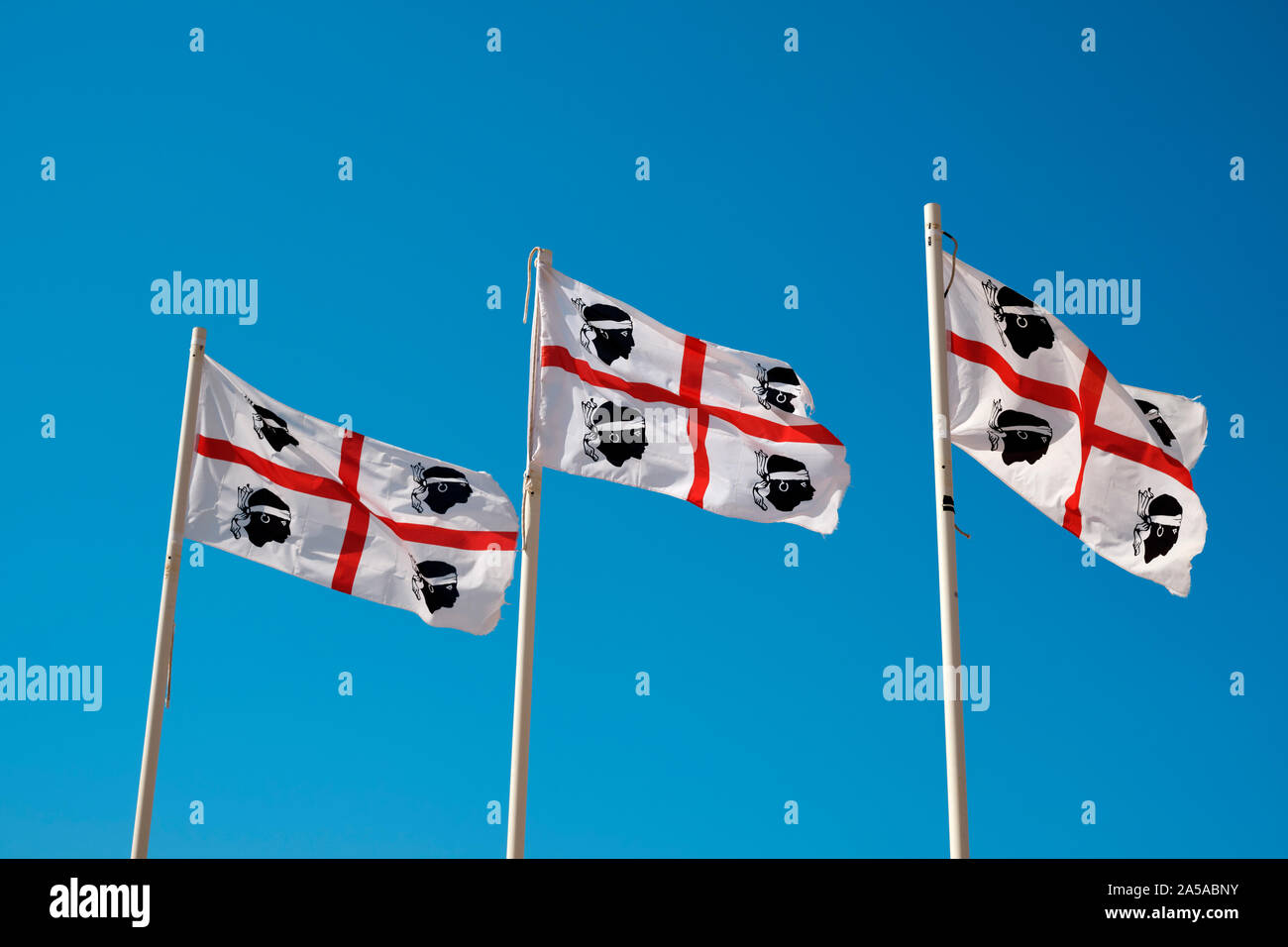 Les drapeaux de la Sardaigne et de la Corse, quatre Maures Flag / pavillon des quatre Maures voler dans un ciel bleu clair Banque D'Images