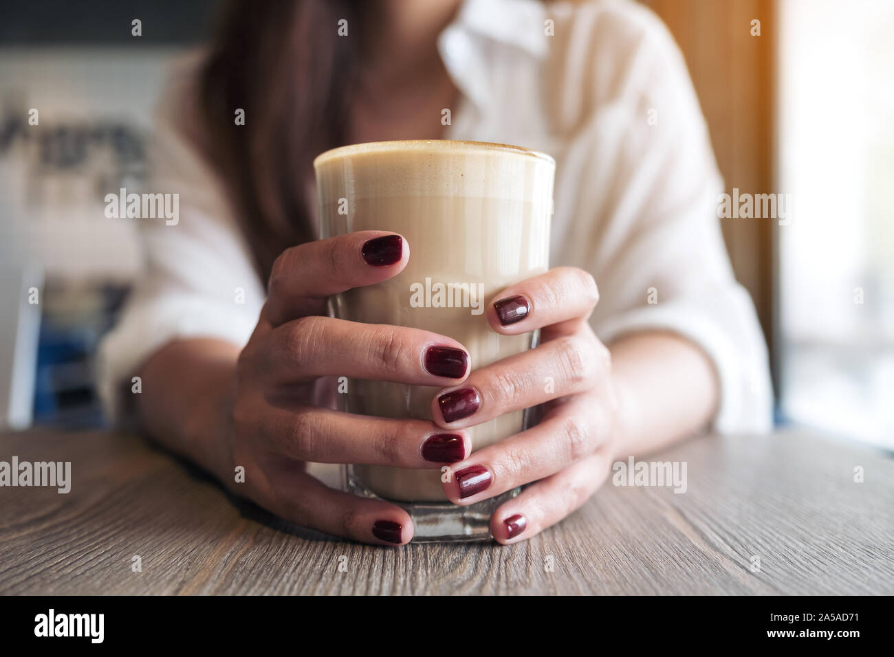 Image Gros plan femme de ses mains avec de la couleur rouge des ongles tenant un verre de café Banque D'Images