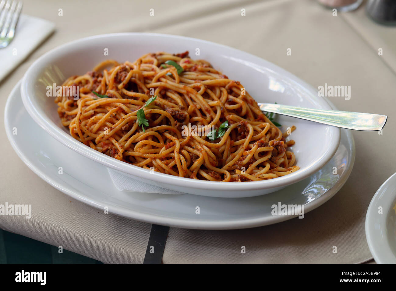 Grande assiette pleine de pâtes à la bolognaise avec une fourchette et garnir du vert. Arrière-plan de couleur neutre table. Délicieux et sain semi italienne. Banque D'Images