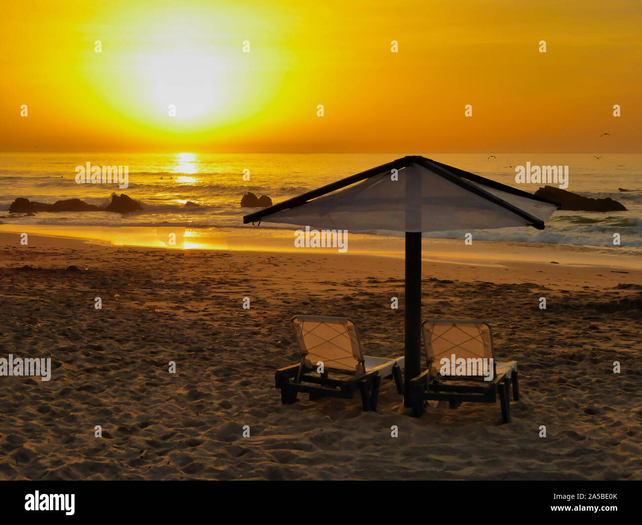 La célèbre plage appelé : Praia do Guincho au Portugal pendant le coucher du soleil avec chaises longues et un parasol Banque D'Images