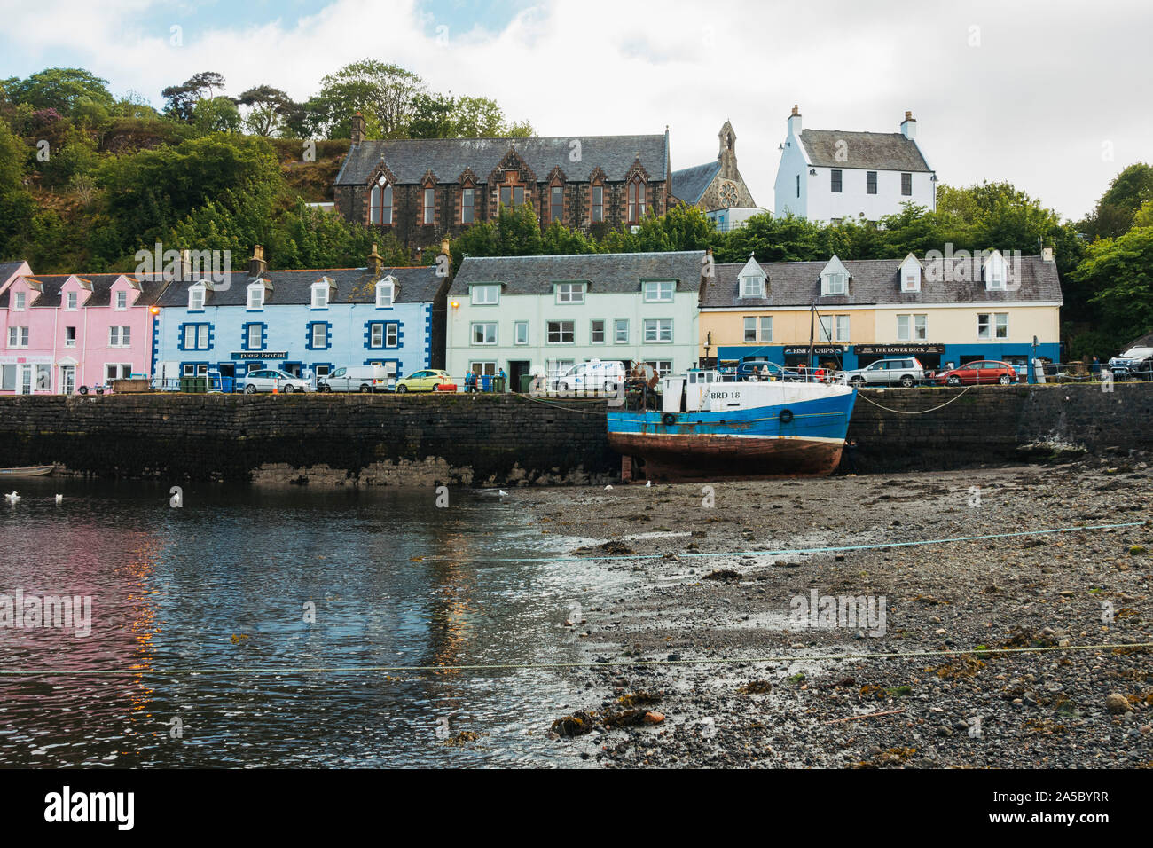 Un bateau, une plage de galets, et le brillant, maisons colorées par le port de Portree, Royaume-Uni Banque D'Images