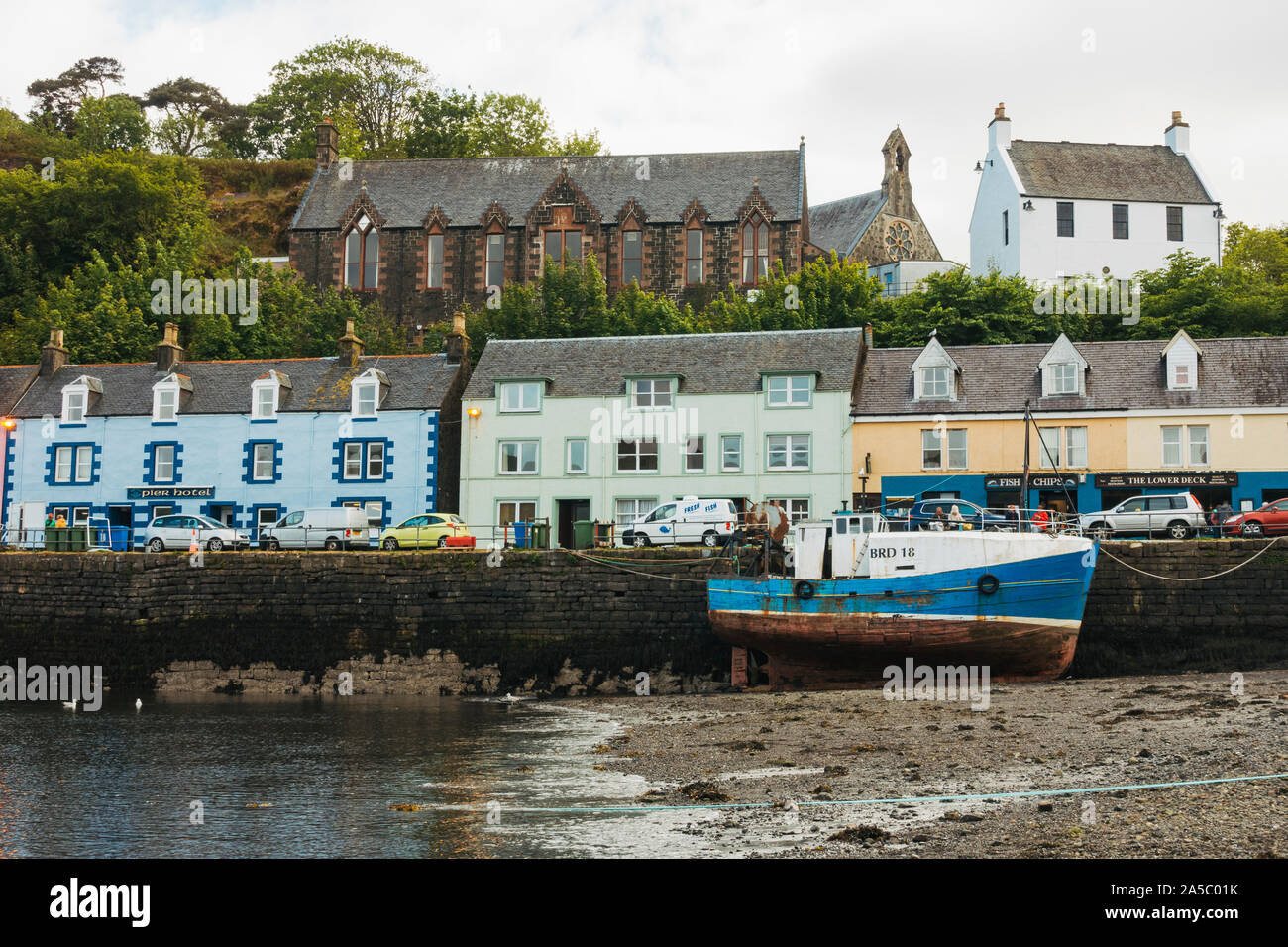 Un bateau se trouve devant des maisons lumineuses, colorées par le port de Portree, Royaume-Uni Banque D'Images