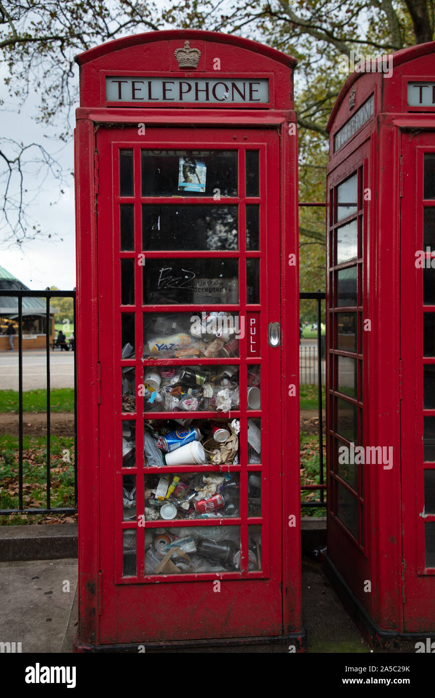 Un téléphone public fort vu la moitié rempli d'ordures et de déchets de plastique et d'aluminium sur Park Lane, Londres, Royaume-Uni. Banque D'Images