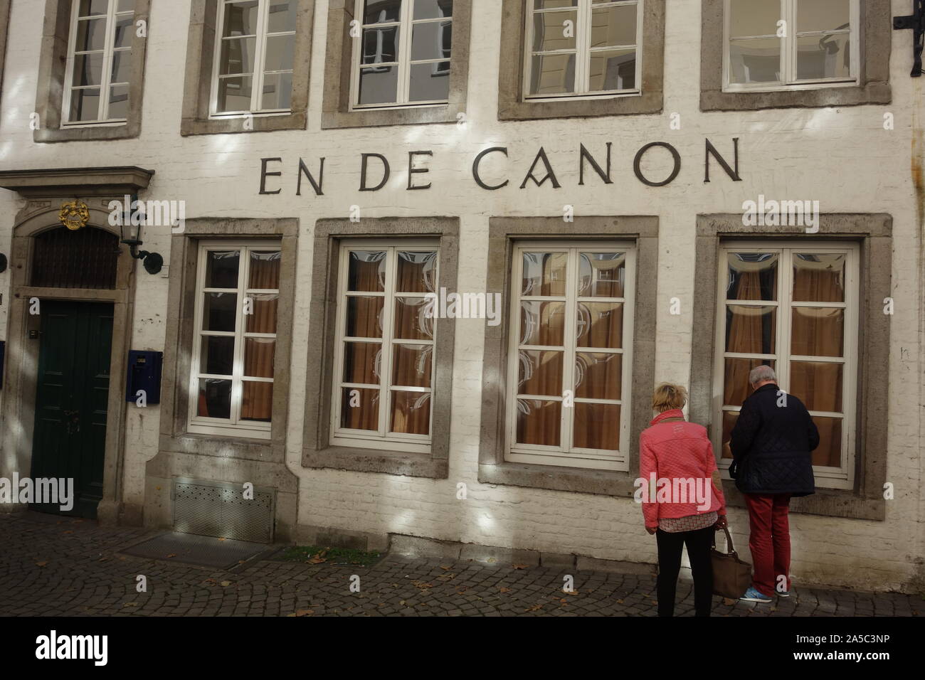 Un couple de personnes âgées a lu le menu dans la fenêtre du restaurant En de Canon du XVIIe siècle à Düsseldorf qui sert des spécialités de Baden. Banque D'Images