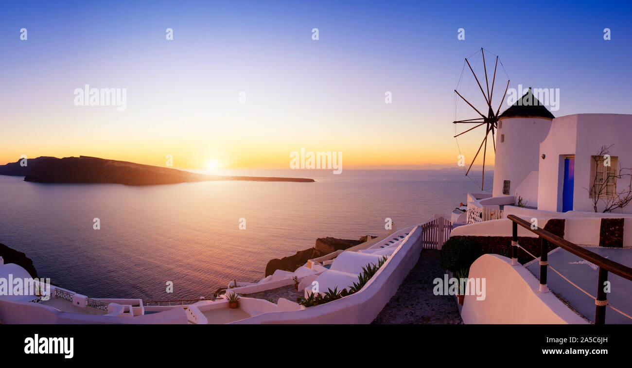 Coucher de soleil sur l'île de Santorin en Grèce. L'église traditionnelle, les appartements et les moulins à vent à Oia village sur un coucher de soleil, photo panoramique. Banque D'Images