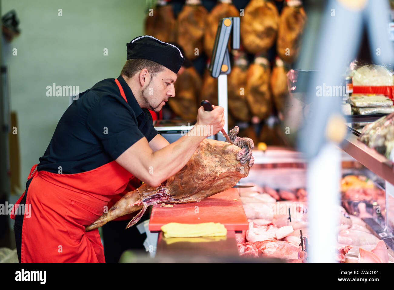 Le désossage boucher un jambon dans une boucherie moderne Banque D'Images