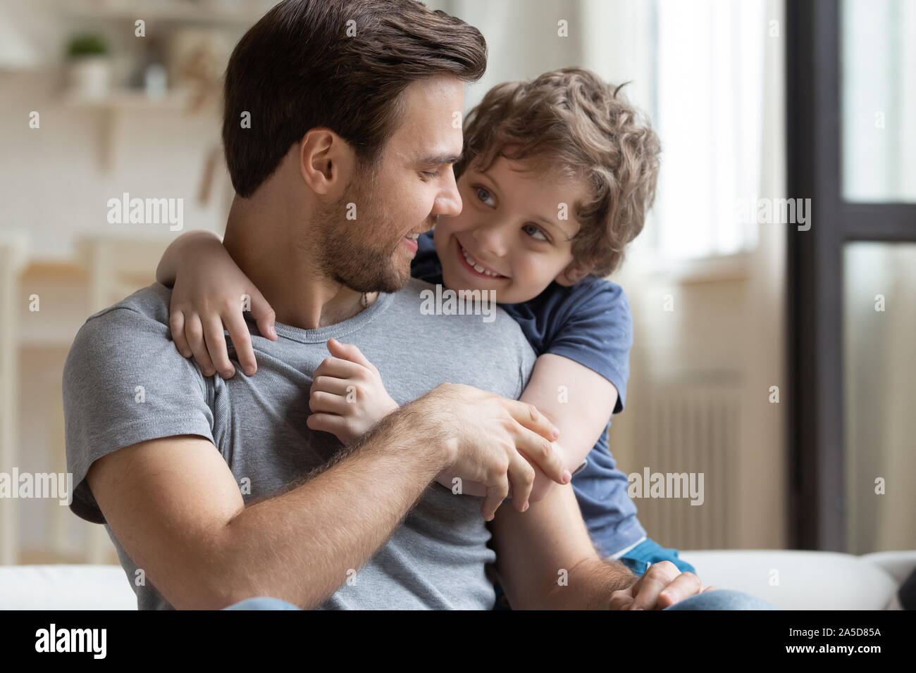 Petit fils hugging heureux père, profitant de moment de tendresse Banque D'Images