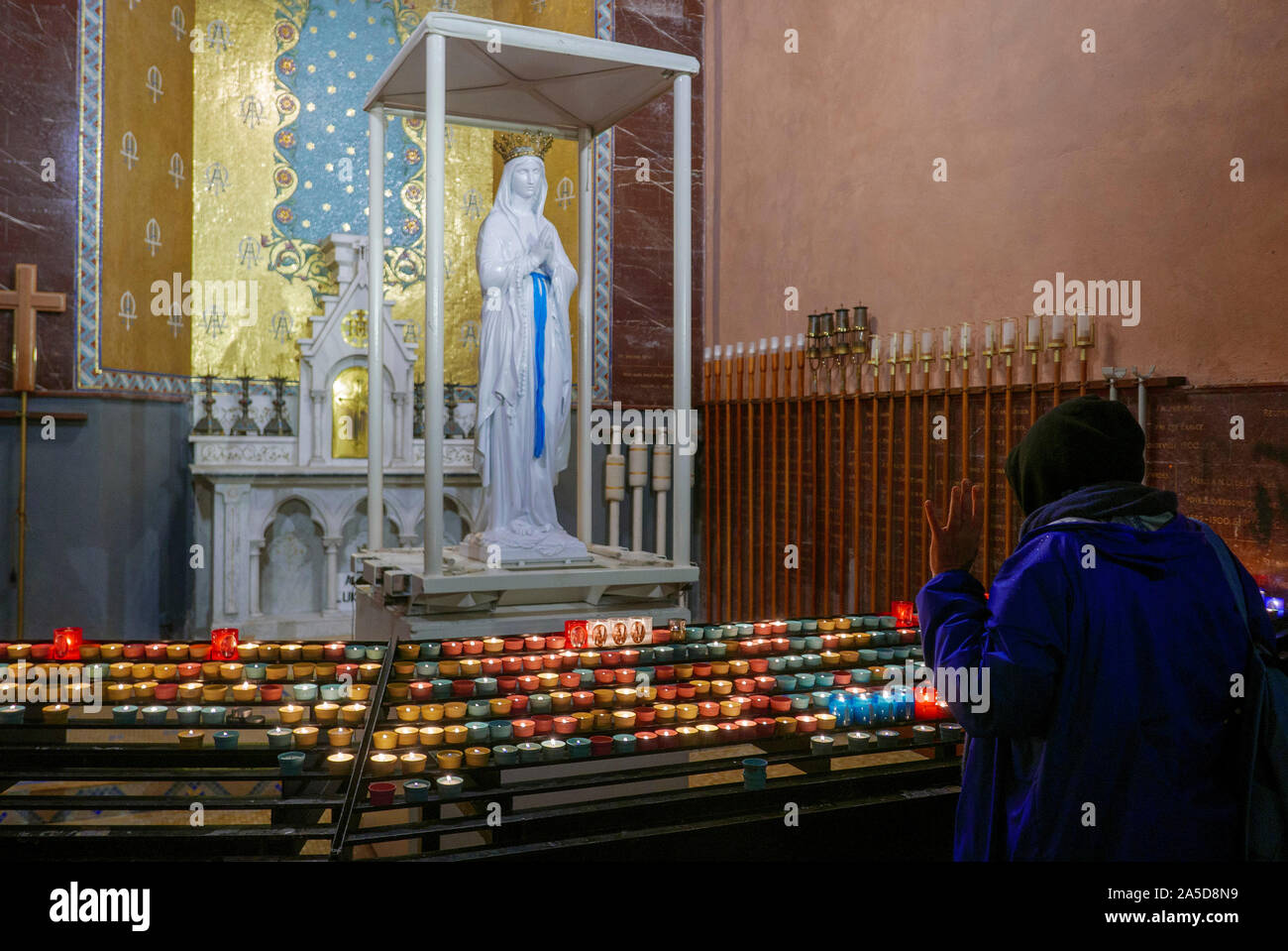 Femme priant à la statue de la Vierge Marie après avoir illuminé une bougie à la basilique notre-Dame du Rosaire dans le Sanctuaire De Notre-Dame de Lourdes, France Banque D'Images