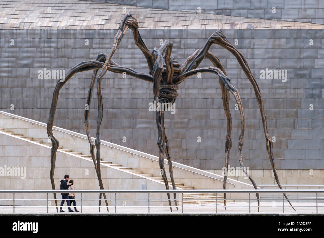 Deux personnes marchant sous la sculpture de l'Araignée géante 'maman' par l'artiste Louise Bourgeois à l'extérieur du Musée Guggenheim à Bilbao, Espagne, Europe Banque D'Images