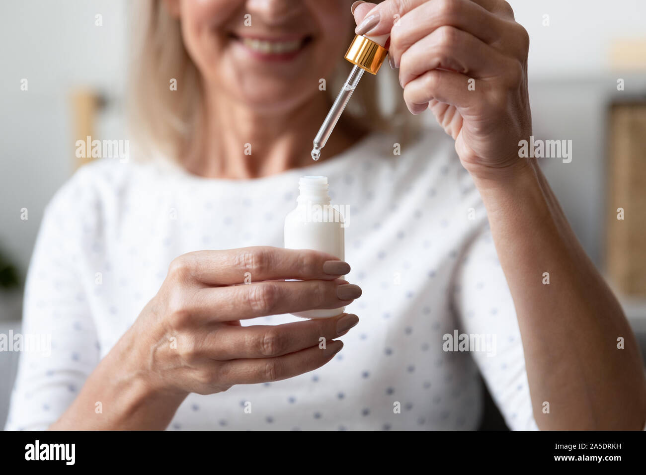 Happy mature woman holding Visage Sérum de soin de peau, Close up Banque D'Images