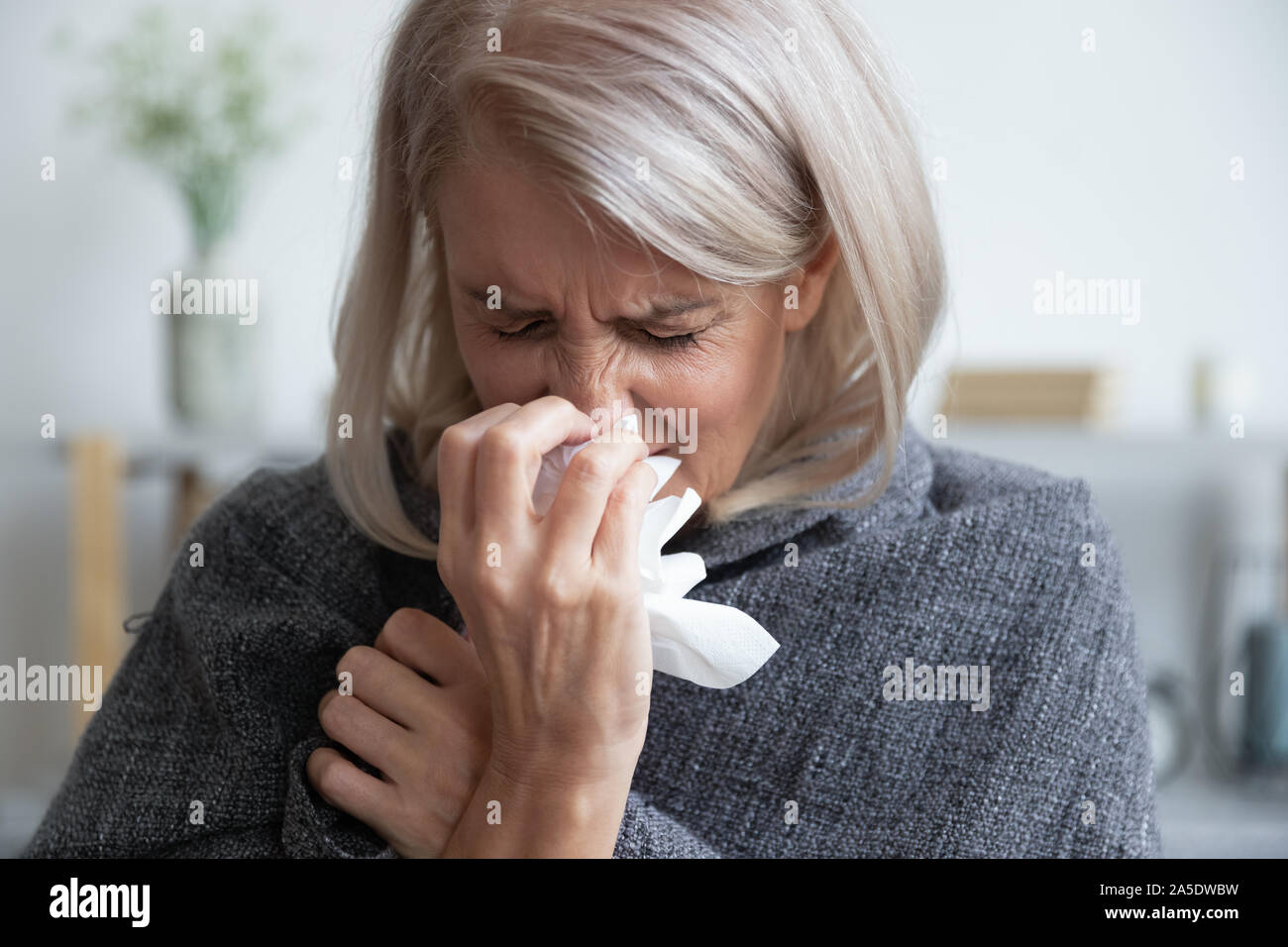 Mauvais mature woman in soufflant d'écoulement nasal éternuements Banque D'Images