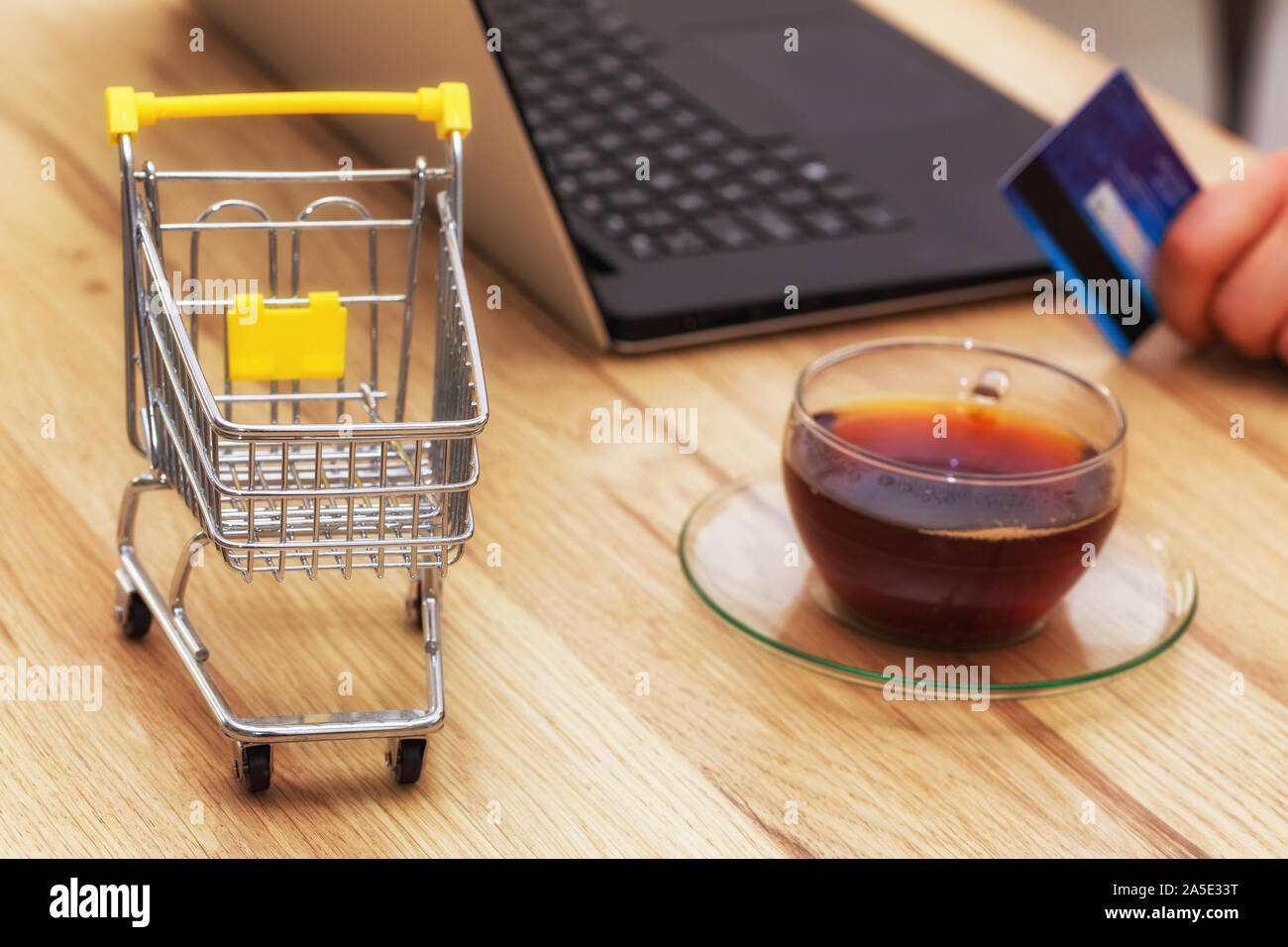 Les achats sur Internet. L'image d'un panier avec ordinateur portable, carte bancaire et un verre de thé. Concept. Shopping pratique sans quitter votre maison Banque D'Images