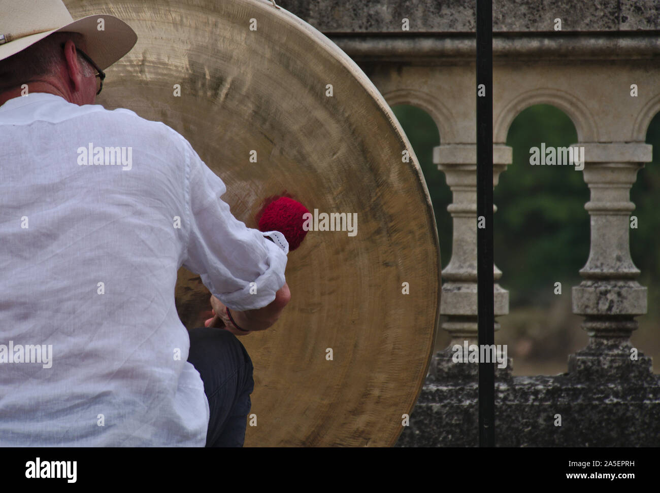 Homme avec une chemise blanche et chapeau de paille à l'gong Banque D'Images