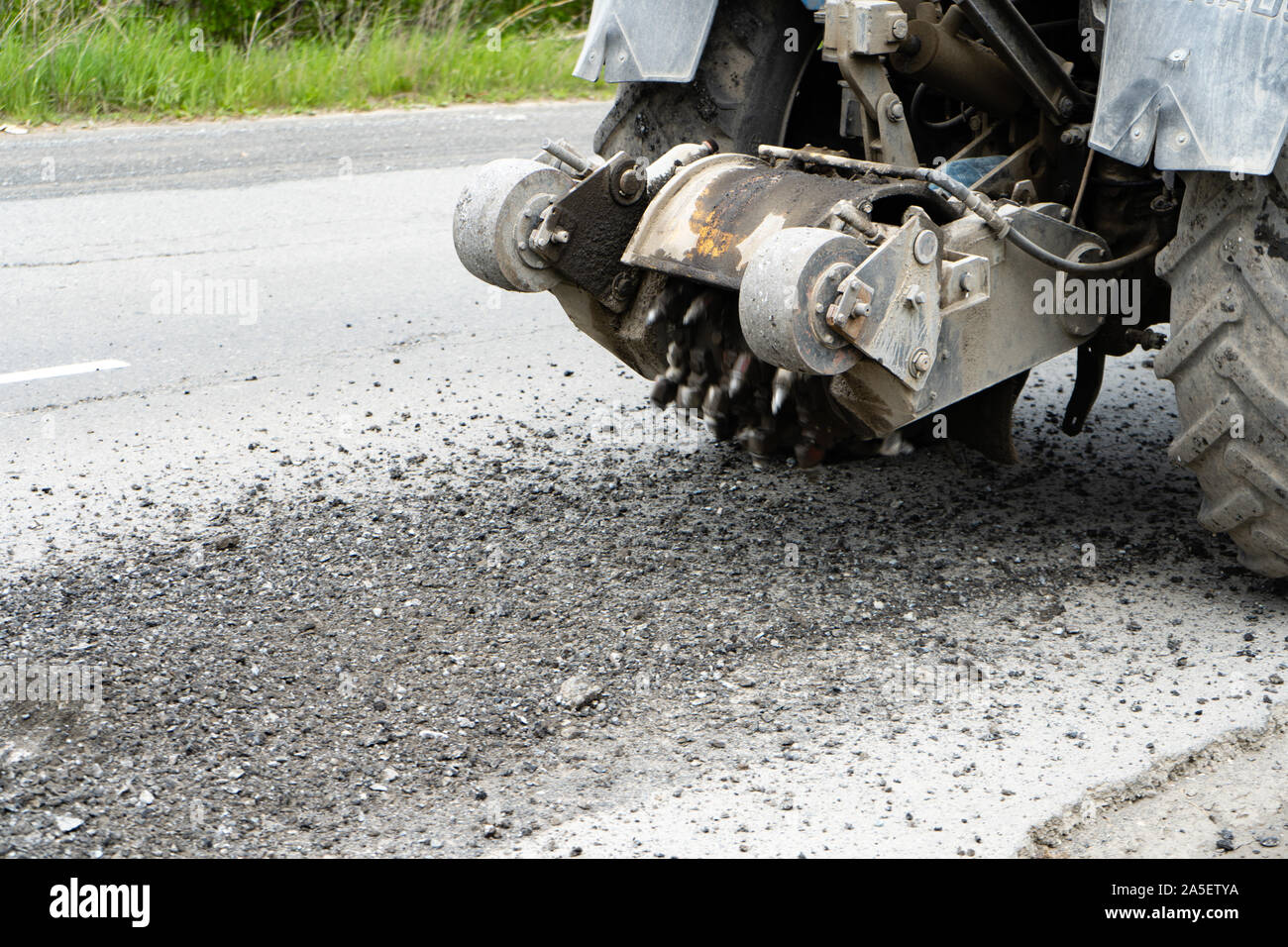 Fraiseuse routière coupe l'ancien de l'asphalte. La réparation des routes. La destruction de la surface de la route. La faucheuse coupe une couche d'asphalte. Pièces de pierre fly apart Banque D'Images