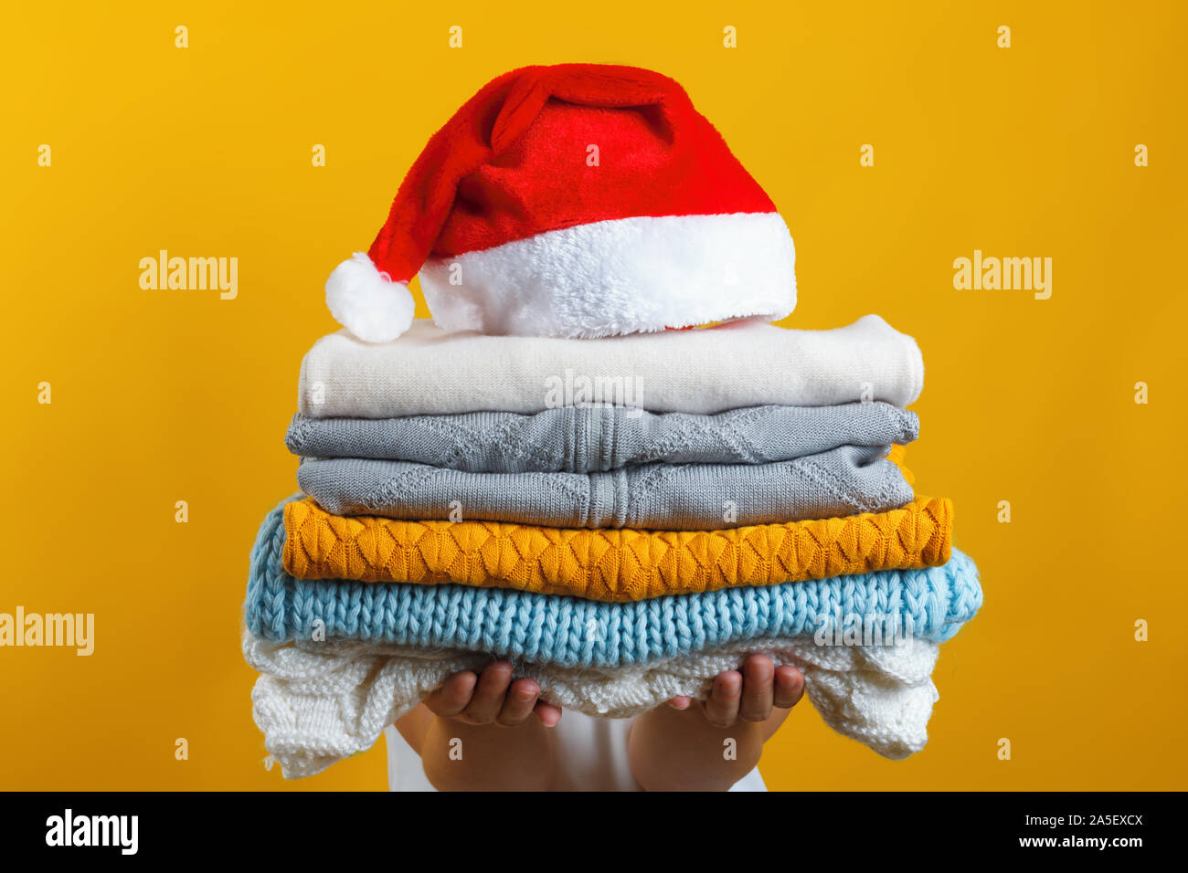 Une femme est titulaire d'une pile de vêtements en tricot chaud, Santa hat est en haut. L'hiver et Noël concept. Banque D'Images