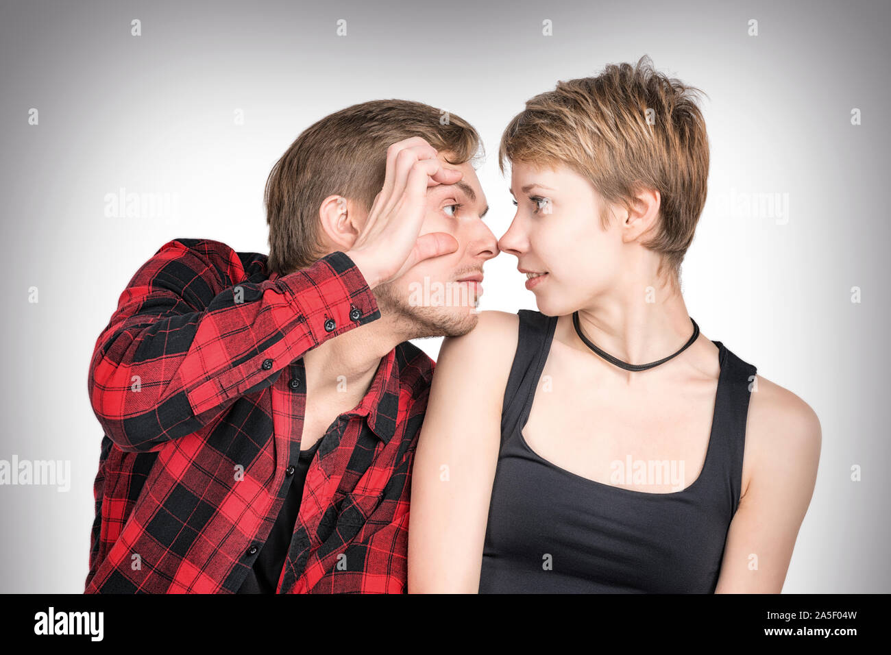 L'homme et la femme assis près l'un de l'autre à la recherche à l'autre. L'homme et de la femme à l'un l'autre. Sur fond gris Banque D'Images