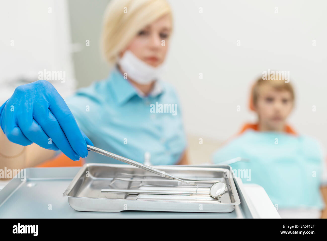 La femme en bleu dentiste femelle frotte picking arsenal dentaire Banque D'Images