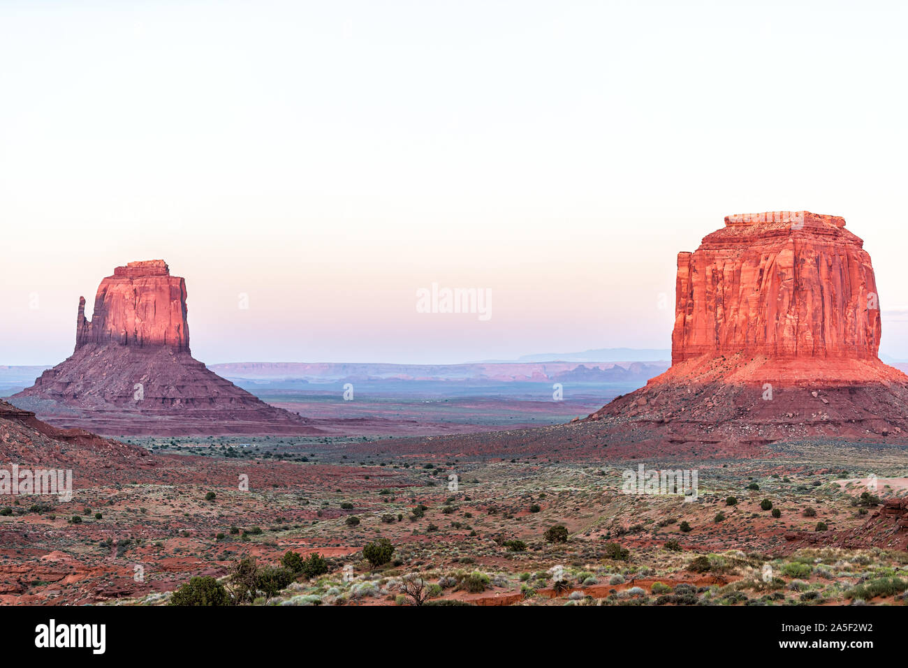 Merrick butte et mitaines rouge avec des formations rock rose couleur dans Monument Valley canyons pendant le coucher du soleil du soleil en Arizona Banque D'Images