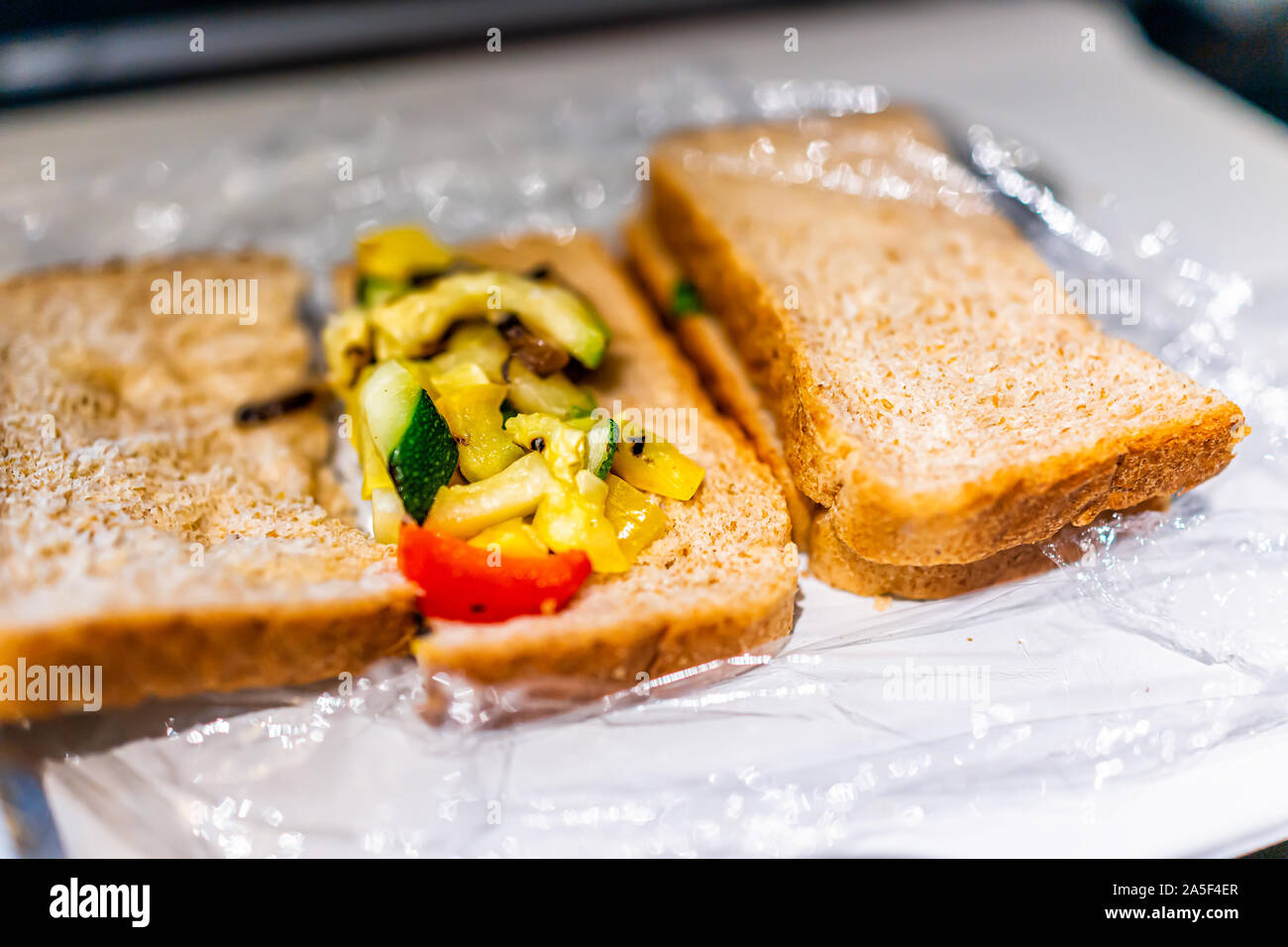 Gros plan du plastique ouvert pain de grains de blé entier sur le bac avec vol de l'avion et croûte de légumes asiatiques comme remplissage repas vegan Banque D'Images