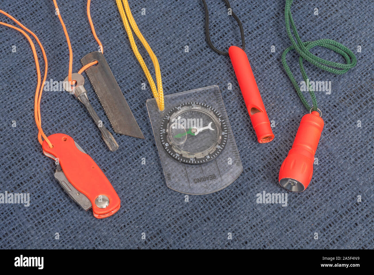 Compétences et équipement de survie. Chasseur de survie à haute visibilité, sifflet de survie, torche de survie à haute viz, couteau à haute viz, boussole de survie, trousse d'urgence. Banque D'Images
