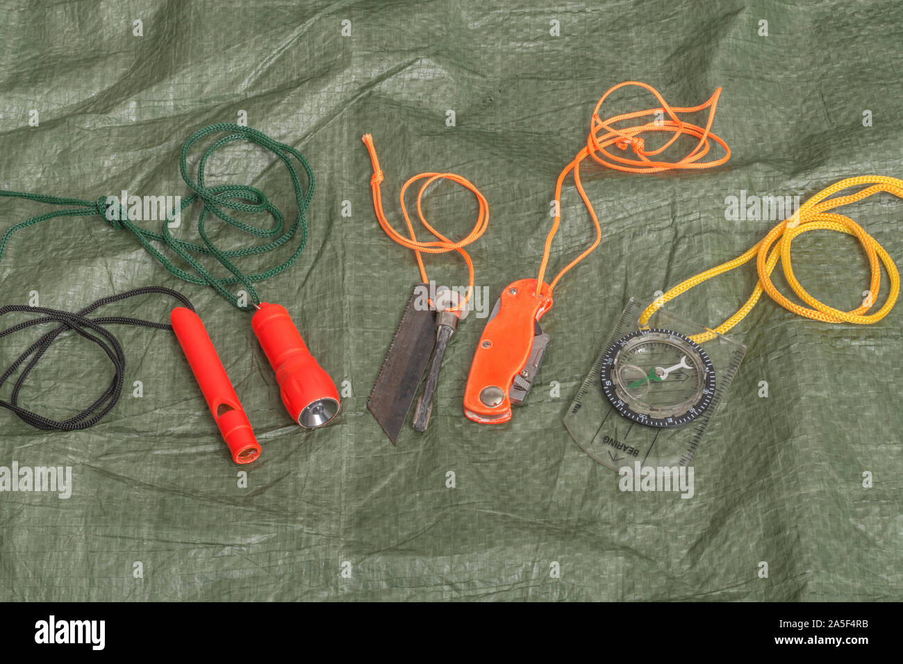 Compétences et équipement de survie. Chasseur de survie à haute visibilité, sifflet de survie, torche de survie à haute viz, couteau à haute viz, boussole de survie, trousse d'urgence. Banque D'Images