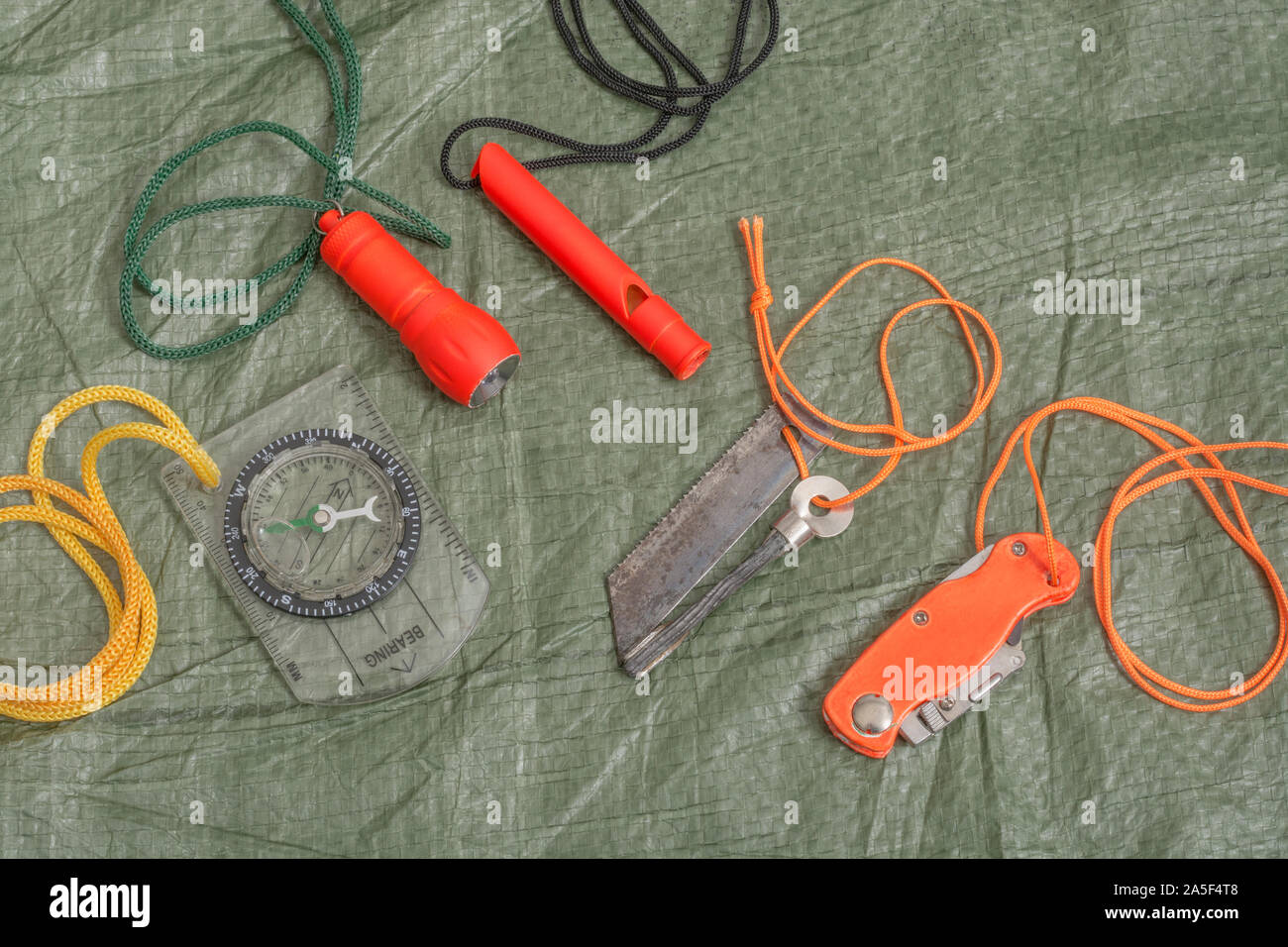 Compétences et équipement de survie. Chasseur de survie à haute visibilité, sifflet de survie, torche de survie à haute viz, couteau à haute viz, boussole de survie, trousse d'urgence. Banque D'Images