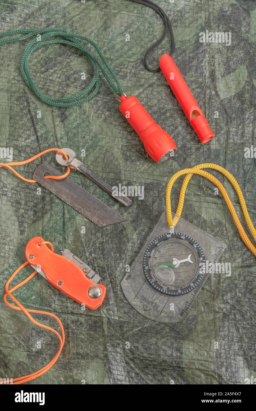 Compétences et équipement de survie. Chasseur de survie à haute visibilité, sifflet de survie, torche de survie à haute viz, couteau à haute viz, boussole de survie, trousse d'urgence. Banque D'Images