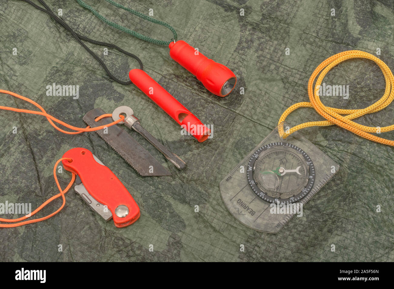 Compétences et équipement de survie. Chasseur de survie à haute visibilité, sifflet de survie, torche de survie à haute viz, couteau à haute viz, boussole de survie, trousse d'urgence. Banque D'Images