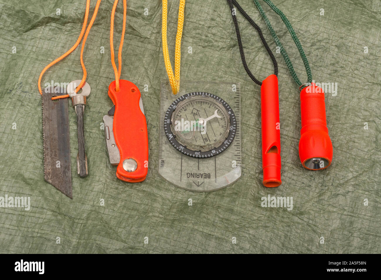 Compétences et équipement de survie. Chasseur de survie à haute visibilité, sifflet de survie, torche de survie à haute viz, couteau à haute viz, boussole de survie, trousse d'urgence. Banque D'Images