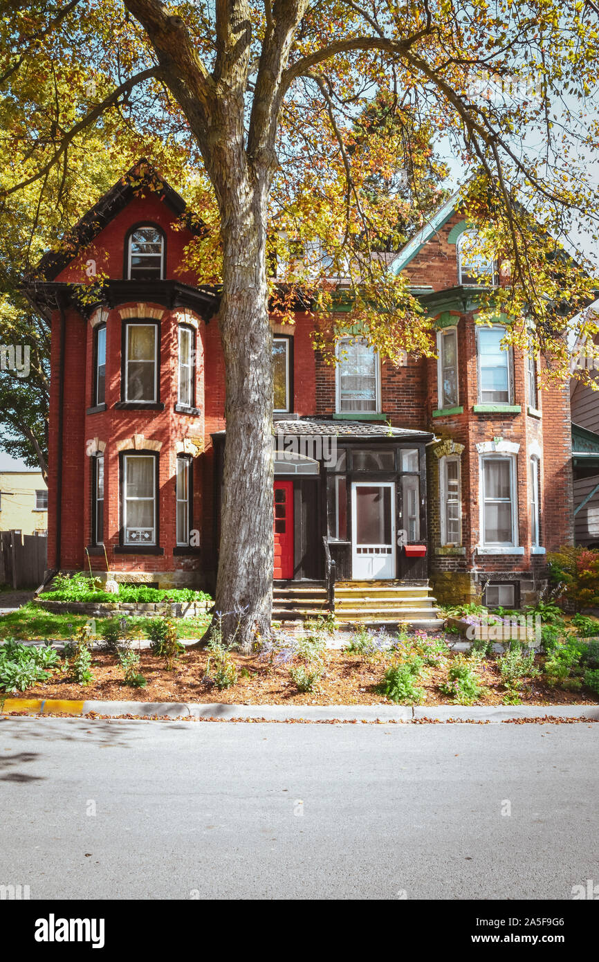 Maisons de briques rouges et mansardes avec jardin et d'arbre en automne. Gananoque, Canada. Banque D'Images