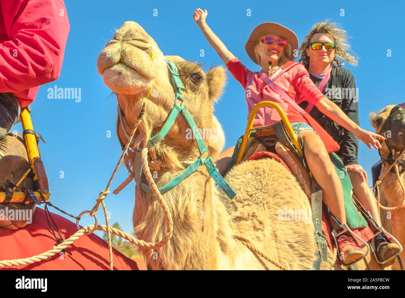 Heureux couple chameau en caravane de chameaux. Le désert australien du Territoire du Nord. Les touristes blancs bénéficie d'chameau sur dunes rouges dans le centre Banque D'Images
