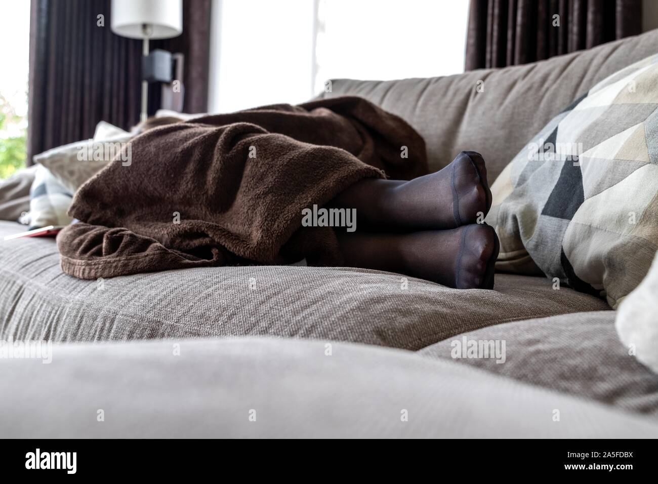 Un Potrait d'un collant noir filles pieds alors qu'elle est en train de  dormir dans le canapé dans le salon sous une couverture chaude brune Photo  Stock - Alamy