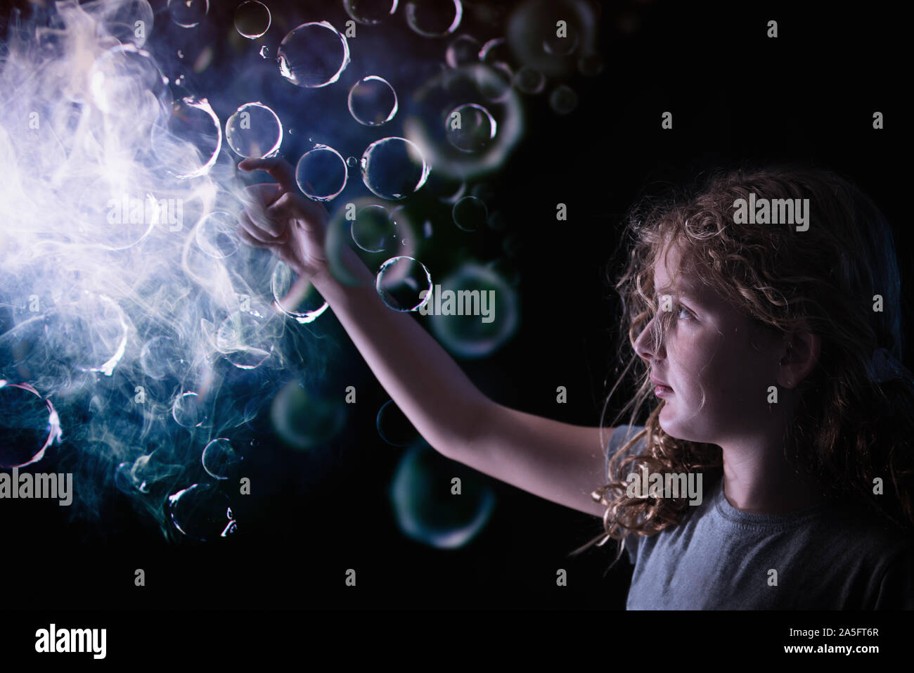 Fille jouant avec des bulles dans la lumière Banque D'Images