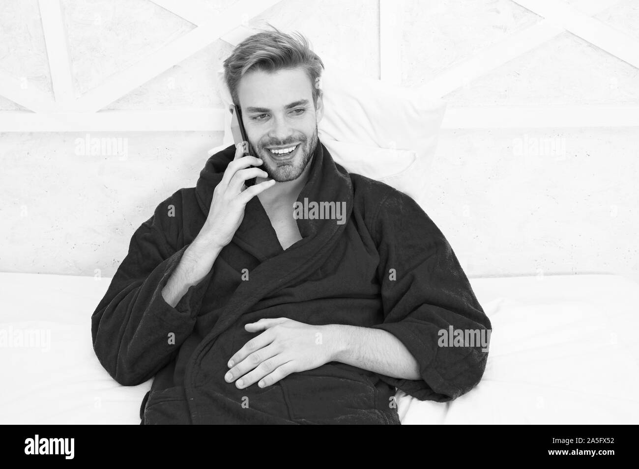 Le meilleur téléphone pour rester en contact. Happy man talking on mobile phone in bed. Beau portrait of smiling guy lors de son appel téléphonique. Téléphone cellulaire pour usage personnel. Banque D'Images