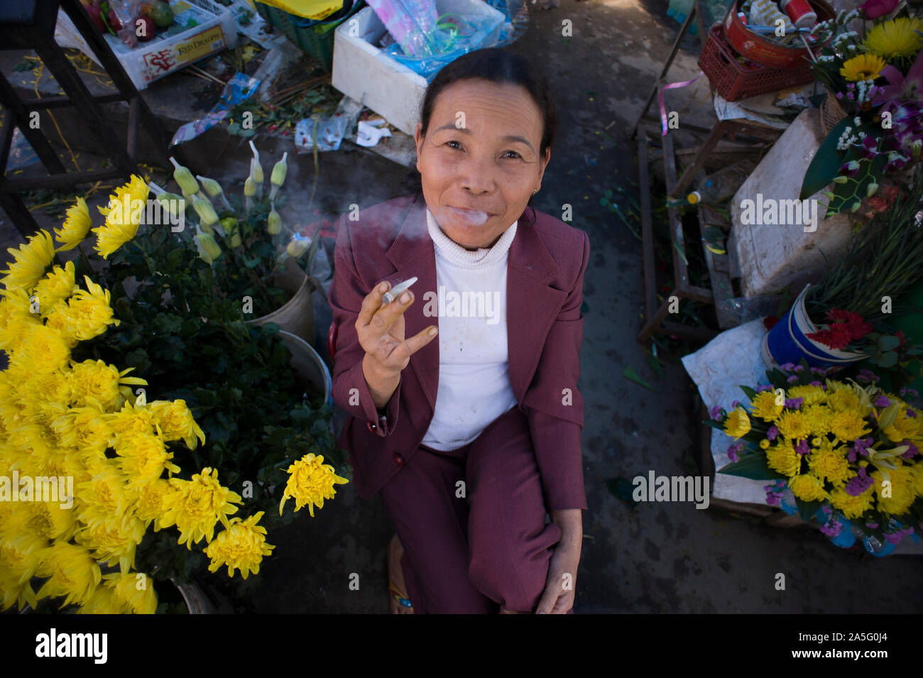 Ho Chi Minh Ville (Saigon), Vietnam - 27 Février 2011 : vendeuse de fleurs vietnamiennes avec anneau de doigt amputé de fumer une cigarette et souriant Banque D'Images