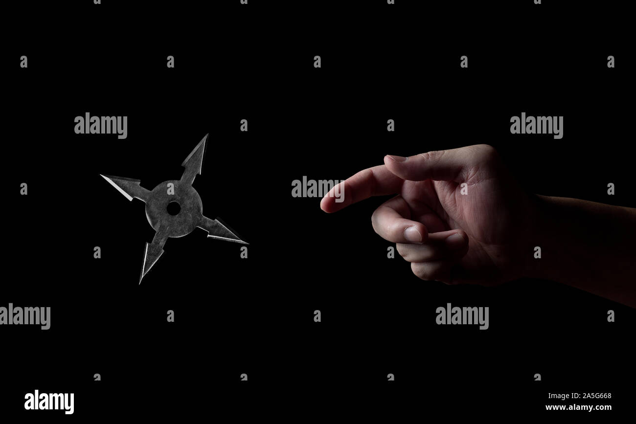 La main libre de lancer Star Ninja Shuriken isolé sur fond noir Banque D'Images