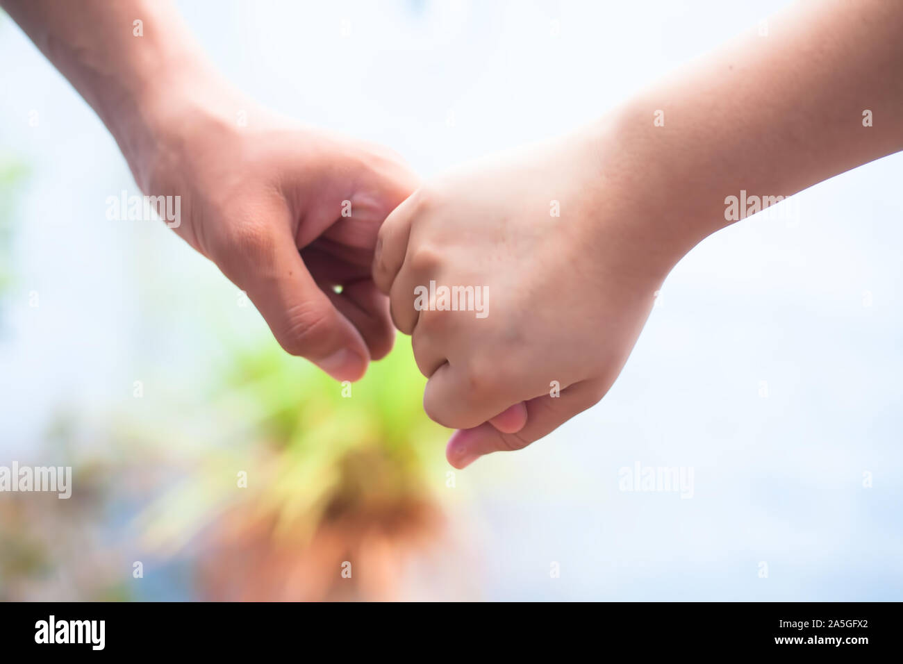 La main de l'enfant de sexe féminin qui tient la main d'un homme tourné avec arrière-plan flou et l'horizontale. Concept de la fête des pères (16 juin). Banque D'Images