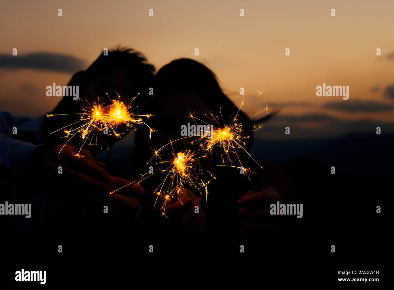 Cierges brûlent d'éclairage dans les mains des hommes et des femmes plus sombre nuit fond coucher de soleil Banque D'Images