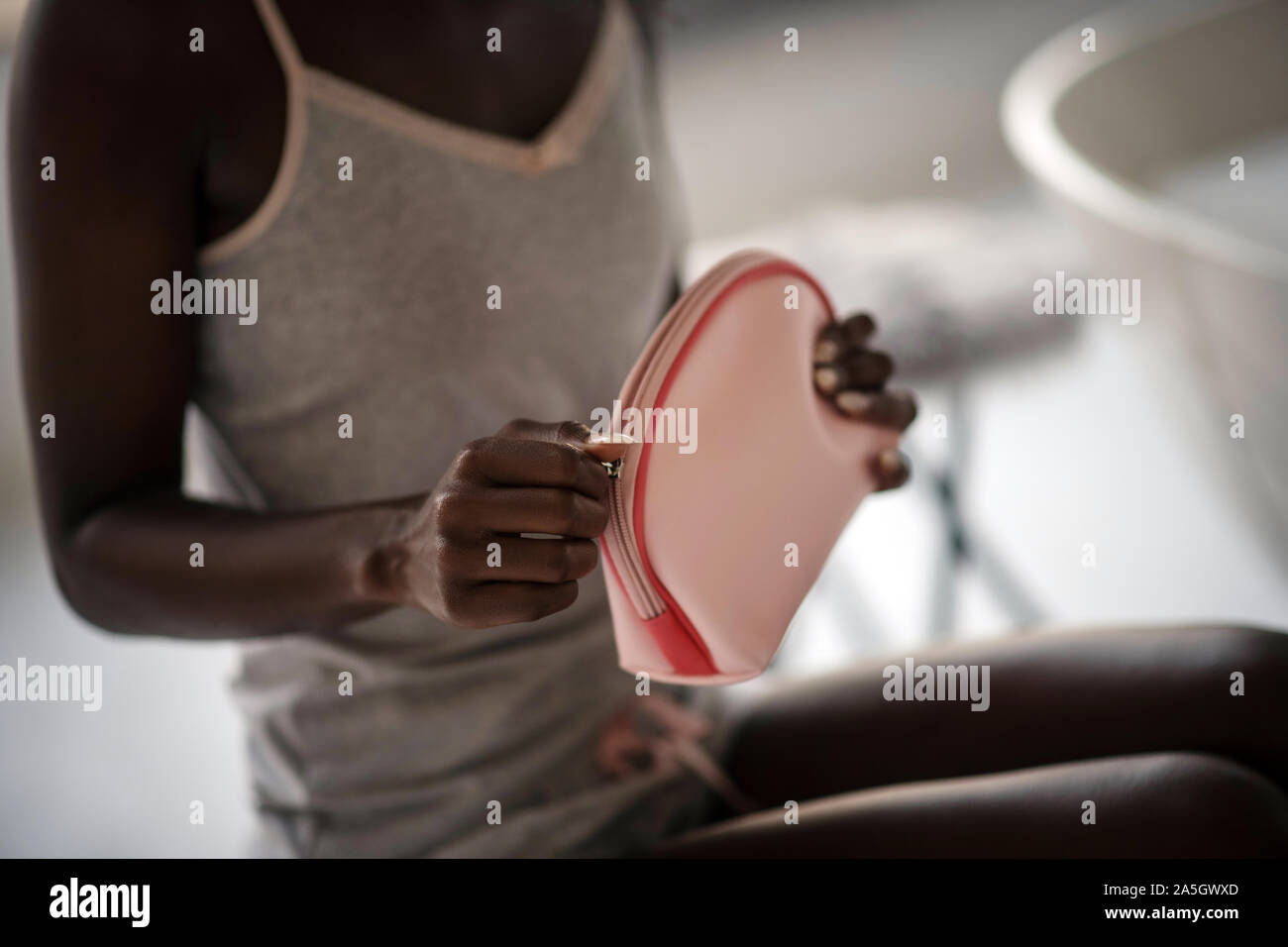 Femme afro-américaine tenant son sac à cosmétiques rose Banque D'Images