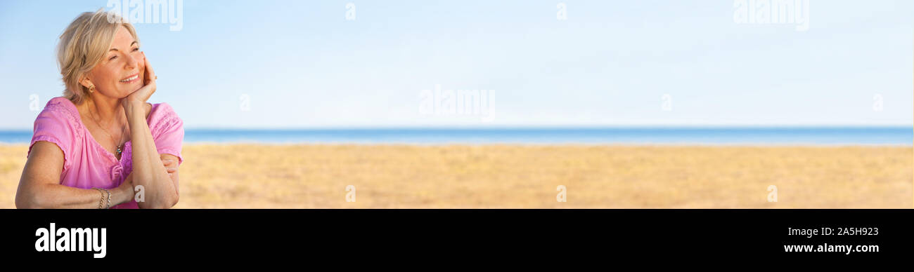 Portrait panoramique de retraités de l'élégant et attrayant réfléchie happy senior couple assis dehors sur une plage face à la mer et ciel bleu sur l'h Banque D'Images