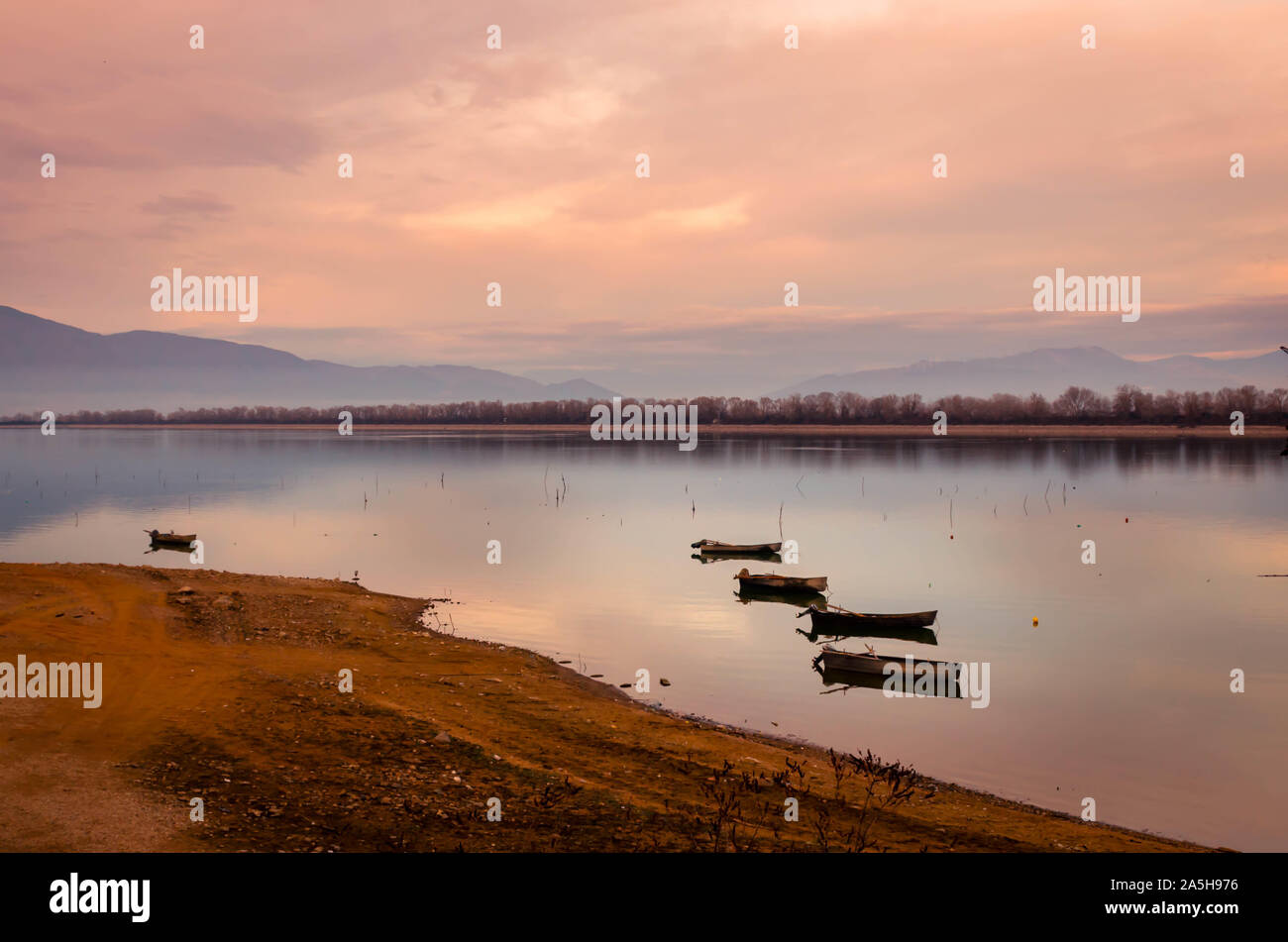 Bateaux en bois flottant sur l'eau calme du lac de Kerkini au coucher du soleil. Banque D'Images