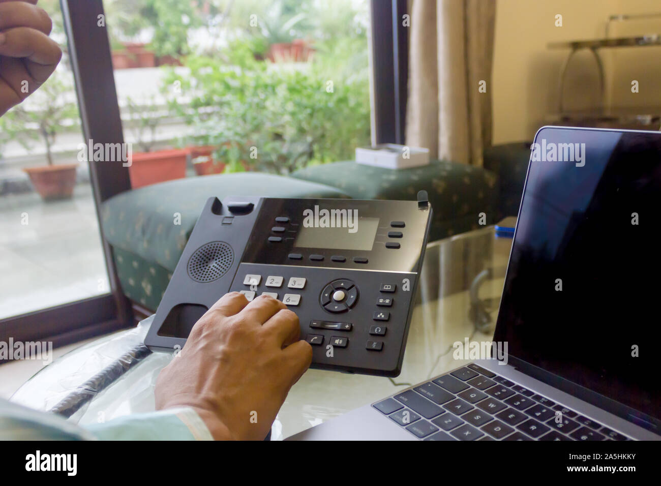 L'homme d'affaires de la composition d'un numéro sur un téléphone fixe lors de l'utilisation d'ordinateur de bureau en bureau. Au cours de l'épaule. Libre. Financement des entreprises et Banque D'Images