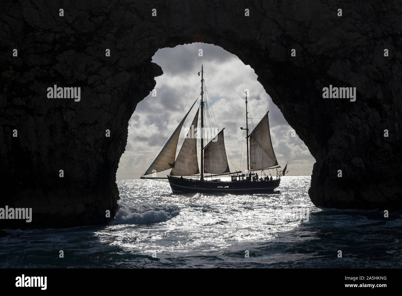 Le Tallship Moonfleet encadrées par l'Arch Rock de Durdle Door, Dorset, UK Banque D'Images