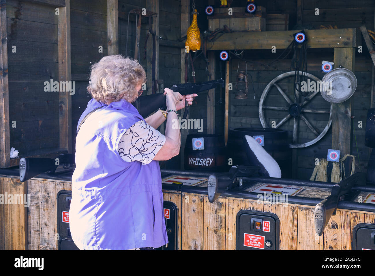 Dame plus âgée avec un jeu shutgun s'amusant à l'arcade de tir sur la jetée de Llandudno Banque D'Images