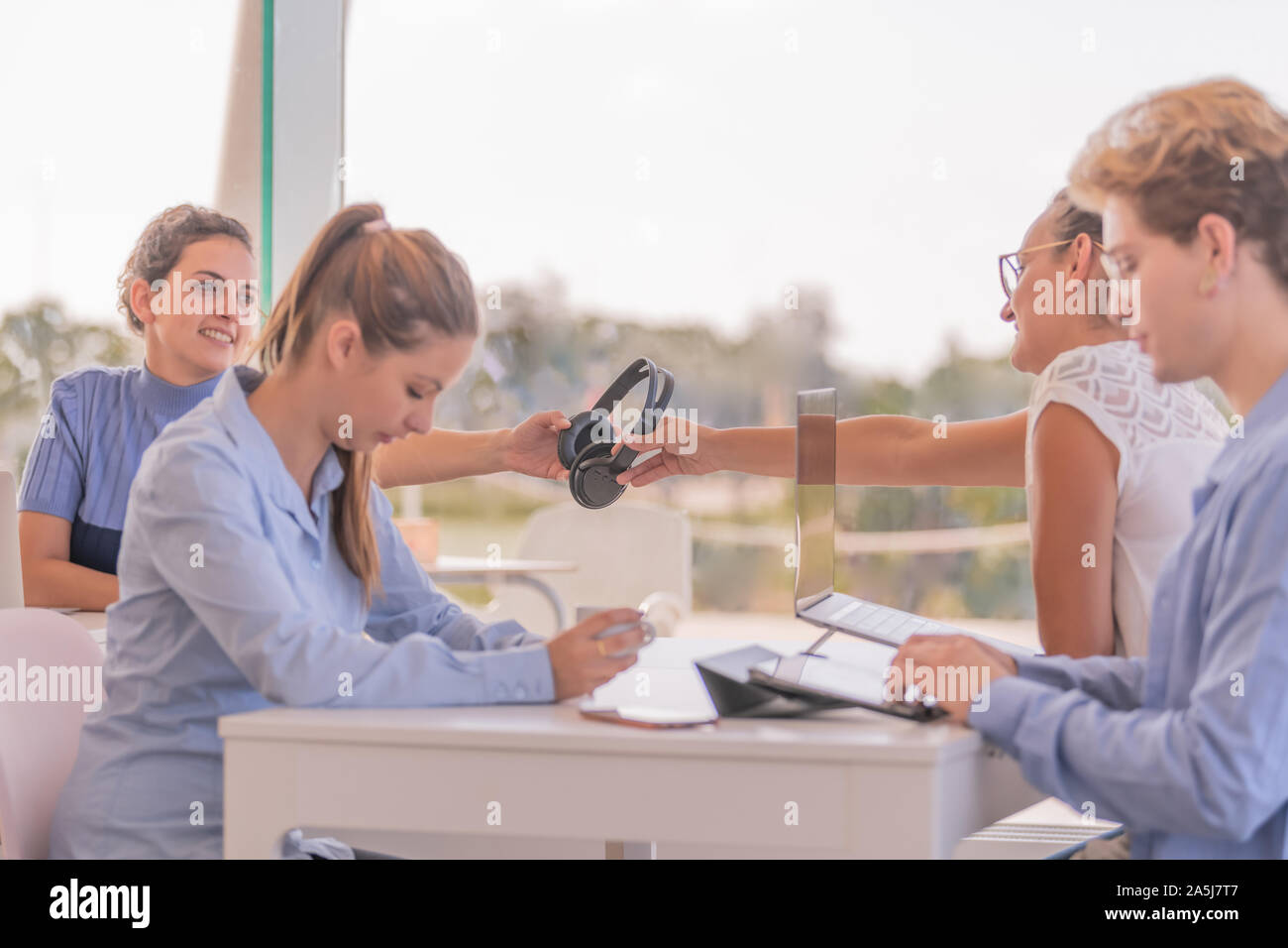 Personnes assises dont trois sont des femmes et deux d'entre eux sont portant des écouteurs avec des ordinateurs à l'avant. Banque D'Images